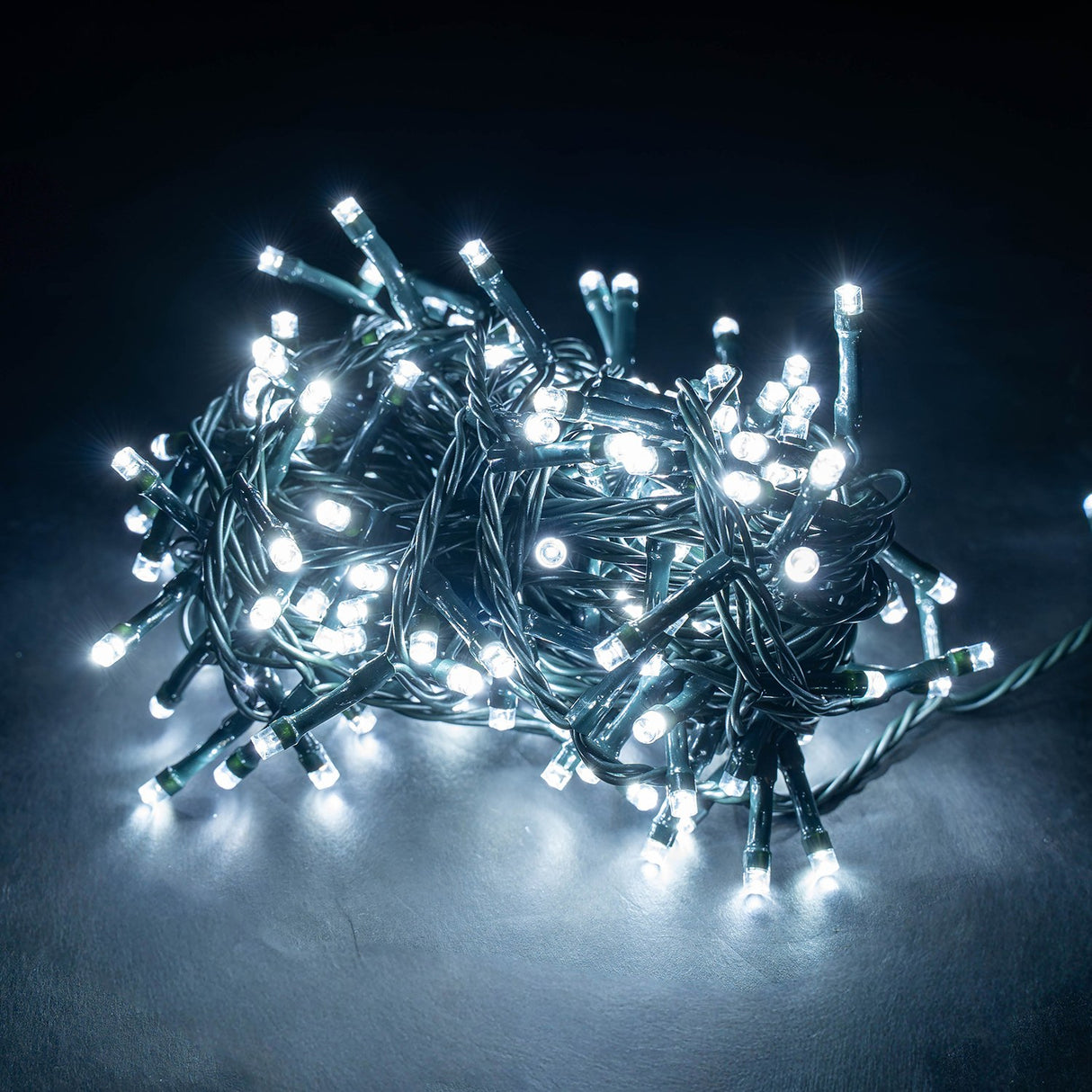 LYYT 200TS-CW cool white LED string lights coiled on a dark green cable, glowing brightly against a dark grey background.