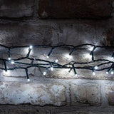 LYYT 200TS-CW cool white LED string lights on dark green cable, draped in rows across a rustic exposed brick wall.