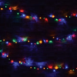 LYYT 200 LED RGBA string lights by AVSL draped across a dark brick wall, glowing in red, green, blue and amber along dark green cable.