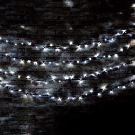 The LYYT 180 LED Heavy Duty Static String Light with its cool white glow and durable black cable casts a soft illumination against the dark brick wall, creating an energy-efficient, cozy, and festive atmosphere.