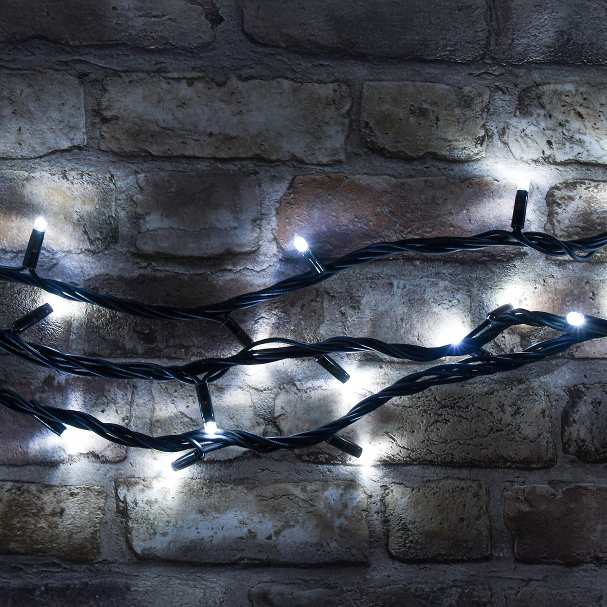 LYYT HD90C-WHT cool white LED heavy duty festoon string lights with concave bulbs on a black rubber cable, draped across a rustic exposed brick wall.