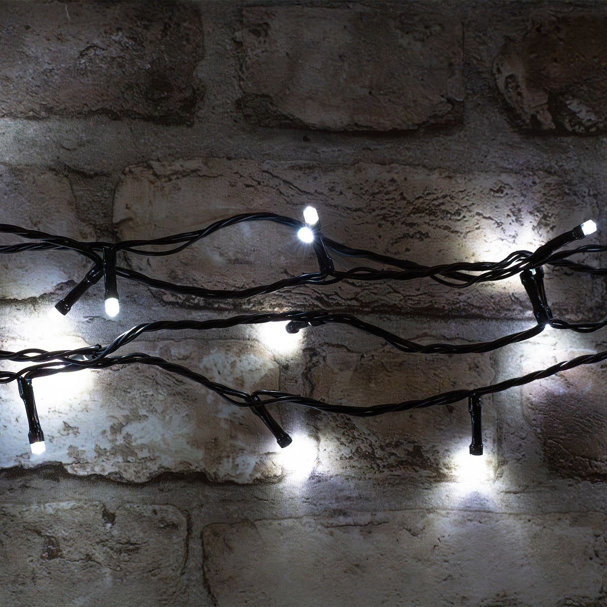 LYYT LED Battery Topiary Ball Light with 120 cool white LEDs on black cable, draped against a rustic brick wall.
