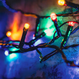 LYYT 120 LED Battery Topiary Ball Light string with multicoloured bulbs on black cable, draped over stone in an outdoor garden setting.