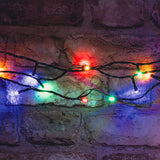 LYYT 120 LED battery topiary ball light string with multicoloured bulbs on black cable, draped across a rustic stone brick wall.