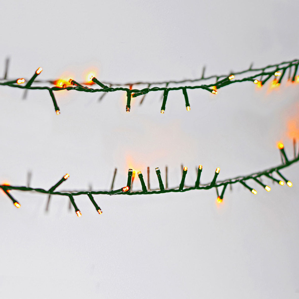 Close-up of the LYYT 45m amber LED string lights showing densely clustered warm amber bulbs along a green cable against a white background.