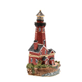 Painted metal trinket box shaped as a red brick lighthouse with gold bands, a blue-stone lantern gallery, and an attached grey-roofed keeper's cottage on a rocky base.