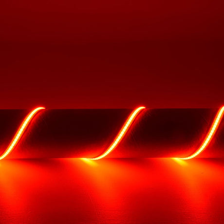 LYYT 24V COB RGB LED strip light by AVSL illuminated in red, arranged in a wave pattern showing the continuous seamless line of light without visible diodes.