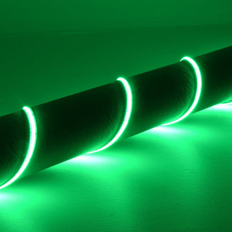 LYYT 24V COB RGB LED strip light wrapped around a cylindrical form, glowing bright green against a light wall in a dim indoor setting.