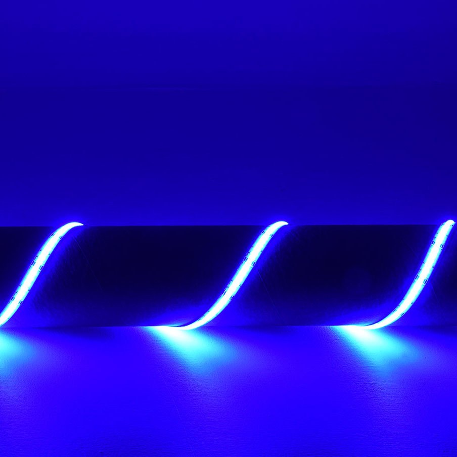 LYYT 24V COB RGB LED strip light by AVSL illuminated in blue, coiled in an S-curve showing the continuous seamless line of light without visible diodes.