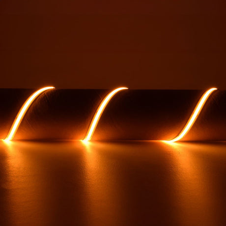 LYYT 24V COB LED strip by AVSL in three warm 2000K amber curves, showing the flexible 5m reel's continuous diffused glow on a dark surface.