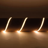 LYYT IP65 24V COB LED strip light draped in three curves over a cylindrical form, emitting continuous warm white 3000K glow against a neutral backdrop.