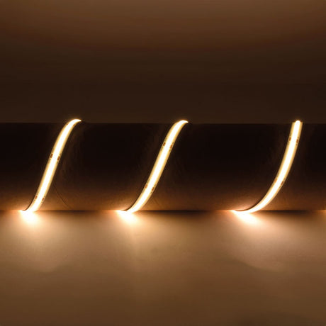 LYYT IP65 24V COB LED strip light draped in three curves over a cylindrical form, emitting continuous warm white 3000K glow against a neutral backdrop.