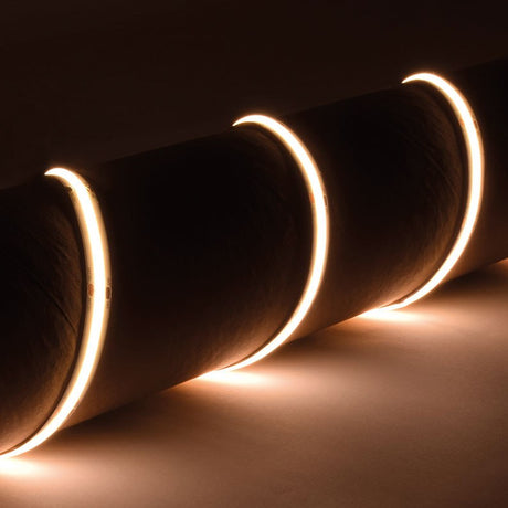 LYYT IP65 24V COB LED strip light by AVSL wrapped around a cylinder, emitting continuous 3000K warm white light in a dark setting.