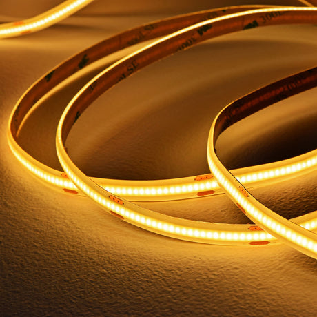 LYYT COB 24V LED tape by AVSL coiled loosely on a neutral surface, emitting a continuous warm white glow with visible 3M adhesive backing.