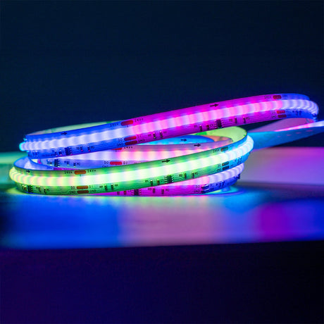 LYYT 24V COB RGB Smart LED tape by AVSL coiled on a dark surface, glowing in blue, green, pink and purple along the 5m reel with visible cut markings.