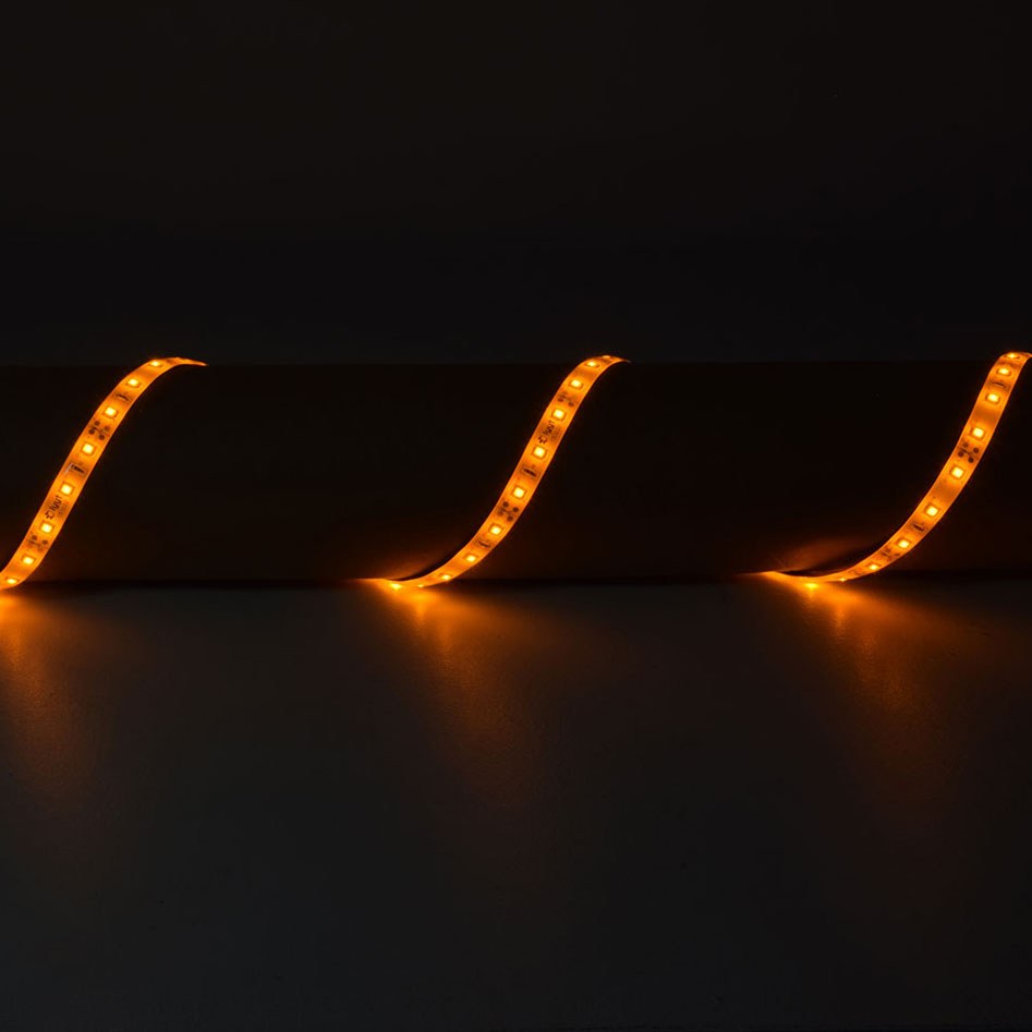 LYYT 12V Amber LED Strip Light draped in three curves over a cylindrical surface, glowing warm amber along the flexible IP65 tape against a dark background.