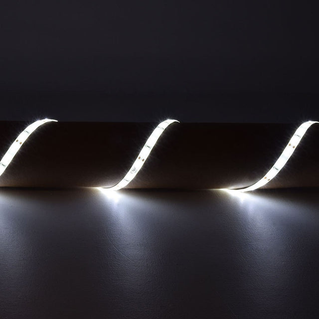 LYYT 12V SMD2835 LED strip light draped in curves over a surface, emitting bright 6000K cool white illumination against a dark background.