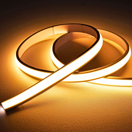 LYYT frosted warm white COB LED tape coiled and illuminated, showing the domed silicone extrusion casting an even 2700K glow across a neutral surface.
