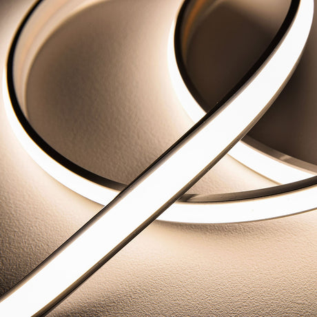Close-up of LYYT Frosted NW COB 24V LED tape curved on a textured wall, its domed silicone extrusion casting a smooth line of natural white light.