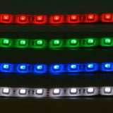 AVSL LYYT 24V RGB LED strip light shown in four segments illuminated red, green, blue, and white on a white silicone backing with IP65 coating.