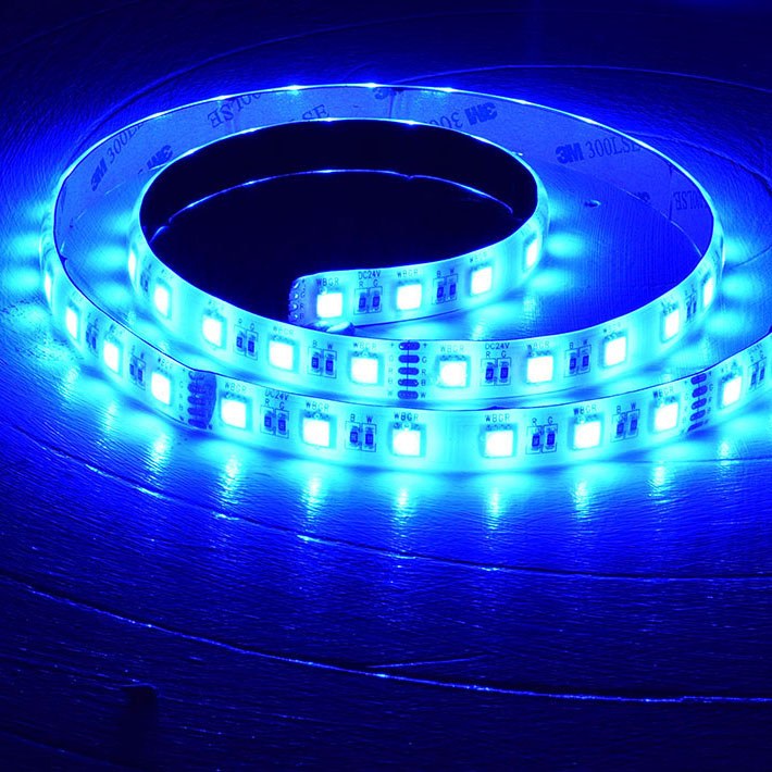 LYYT 24V RGBW LED strip light coiled on a wooden surface, illuminated in bright blue across the 5m reel with visible SMD LEDs and 3M adhesive backing.
