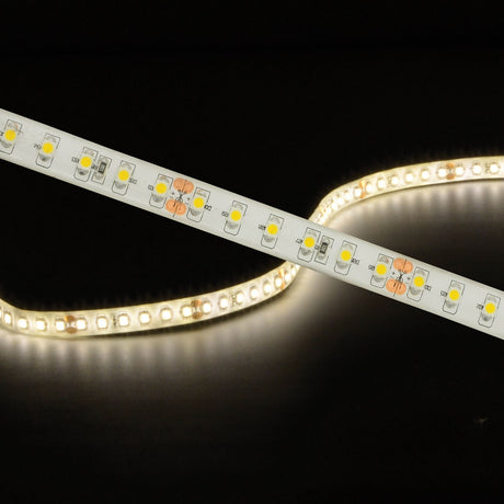 LYYT 24V LED strip light coiled and illuminated in warm white 3000K, showing visible SMD LEDs, cut marks and solder pads along the white flexible tape.