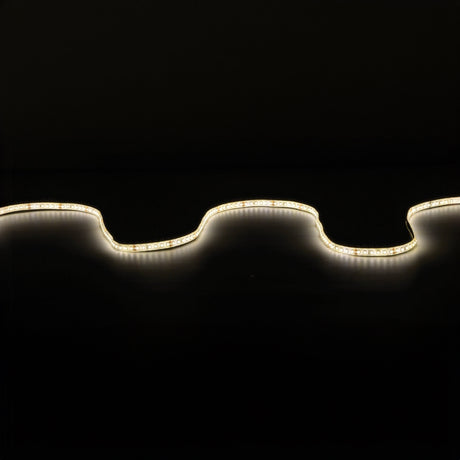 The LYYT 24V High Output LED Strip Light 5m - 3000K emits a gentle glow against a dark backdrop, forming an undulating line of light. Its high luminous flux accentuates the strip's curves and contours, offering warm illumination.
