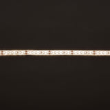 LYYT LT245120-NW LED strip tape illuminated in natural white, showing densely spaced LEDs along the silicone-coated IP65 strip against a dark background.