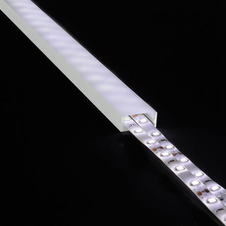 LYYT Wide Crown 1m surface-mount aluminium LED profile with frosted polycarbonate diffuser, illuminated with LED strip partially extending from the channel.