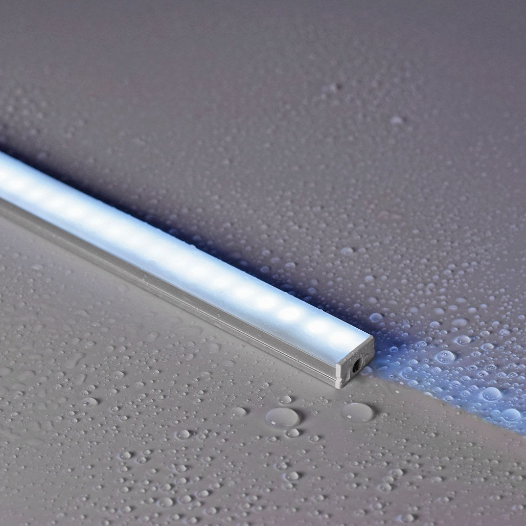 LYYT IP68 waterproof aluminium LED profile by AVSL, illuminated on a wet grey surface with water droplets, showing the frosted diffuser and end cap.