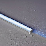 LYYT IP68 waterproof aluminium LED profile by AVSL, illuminated on a wet grey surface with water droplets, showing the frosted diffuser and end cap.