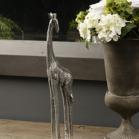 Libra Interiors Textured Electroplated Giraffe Sculpture in silver resin, displayed on a wooden surface beside a bronze urn of white hydrangeas.