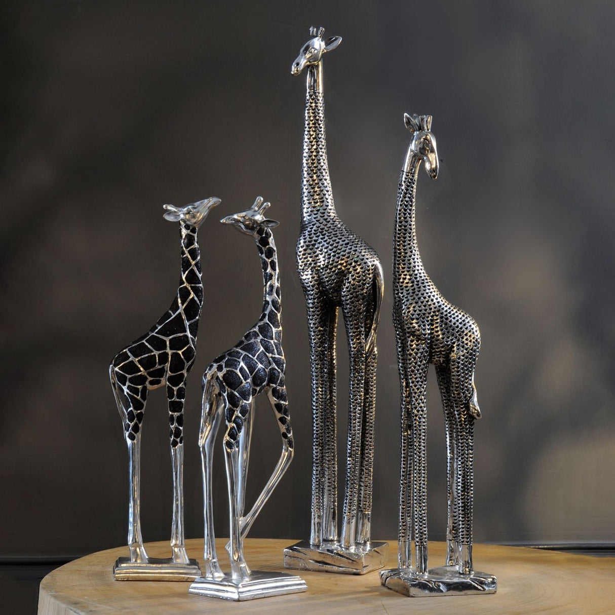 Libra Interiors Textured Electroplated Giraffe Sculptures in silver, four resin figures with black-recessed textured coats grouped on a wooden surface.