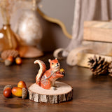 Red Squirrel and Pine Cone Hinged Metal Trinket Box in glossy russet brown with cream accents and crystal detailing, displayed on a wood slice amid acorns and pine cones.