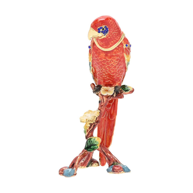 Red macaw metal trinket box with hinged lid, enamelled in red, yellow, green and blue with gold-tone feather detailing, perched on a flowering branch base, shown on a plain white background.