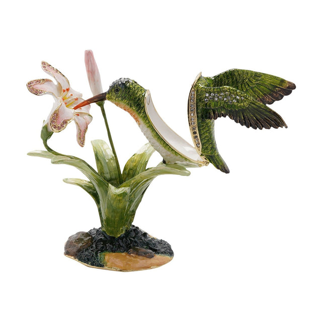 Hummingbird and Lily Metal Trinket Box in glossy green, with white breast and orange throat, hinged wing opening beside a pink-and-white lily on a rocky base, shown on a white background.