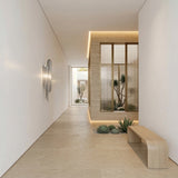 Minimalist hallway with light beige floors and walls, a wooden bench, wall art, and an indoor garden behind glass. The Valora 2 Light Metal Chain Veil Wall Light in nickel adds contemporary flair, illuminating vibrant succulents for a welcoming ambiance.