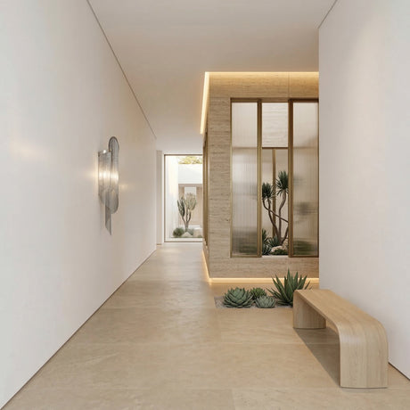 Minimalist hallway with light beige floors and walls, a wooden bench, wall art, and an indoor garden behind glass. The Valora 2 Light Metal Chain Veil Wall Light in nickel adds contemporary flair, illuminating vibrant succulents for a welcoming ambiance.