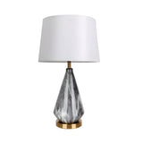 The Calvero 1 Light Diamond Facet Marble Table Lamp features a geometric marble-patterned black and white base, a round brass bottom, and a modern white lampshade.