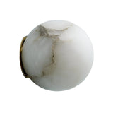 The Alviora 1 Light Large Circular Stone Alabaster Wall Light features a smooth white marble sphere with subtle gray veining and a small brass accent, set against a plain white background.