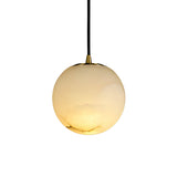 Niori Lyvane medium globe pendant light with a soft white Spanish alabaster shade, brushed brass collar and black flex, shown against a plain white background.