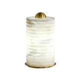 The Aurelior LED Small Ribbed Alabaster Table Lamp – Soft White features a textured, white translucent cylindrical body, gold metallic base, and dome top. It emits soft, diffused light—ideal as a small bedside lamp.