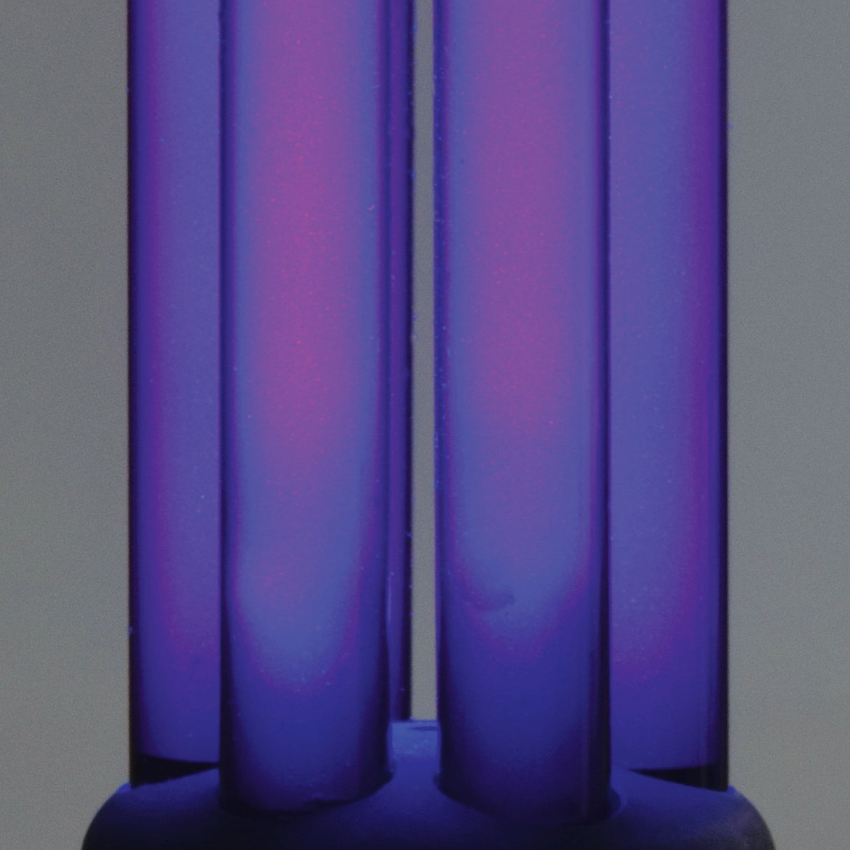 Close-up of the AVSL QTX UV Black Light Bulb B22 20W 365nm twin-tube compact fluorescent lamp glowing purple against a light grey background.