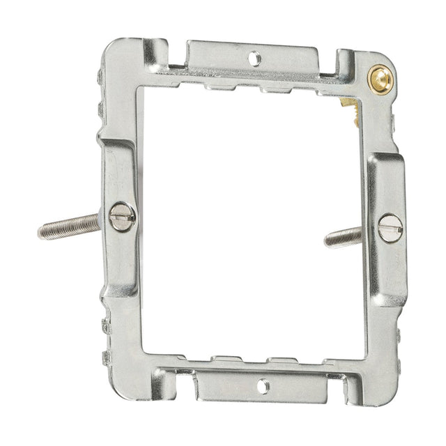 Close-up of the 1-2 Gang Mounting Frame for electrical fixtures, designed in a square shape with curved edge switches. It features two screw holes on opposite sides with screws partially inserted. A small yellowish component is visible at the top right corner, reminiscent of a Knightsbridge design.