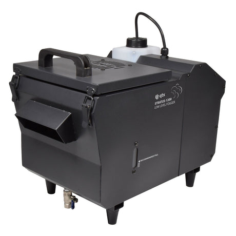 The QTX STRATUS 1200-Low Level Fog Machine is a portable effect device featuring a robust handle, specifically designed to create low-lying fog effects. It includes a fluid container and control panel located on top, side vents for optimal airflow, and stands on four legs to generate captivating ground-hugging mist.