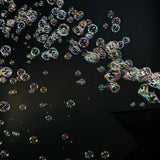 Iridescent bubbles filling a dark stage space, produced by the QTX QTFX-B4 dual wheel bubble machine with four fans.