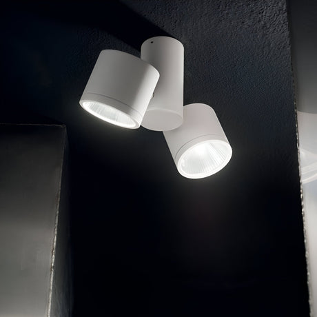 The Beamglasses LED Twin Spotlight 14.5W 4000K - White is a contemporary ceiling-mounted fixture featuring two cylindrical white lamps that contrast beautifully against a dark ceiling. These energy-efficient lights are angled in various directions, casting neutral white light on different sections of the wall.