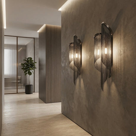 A modern hallway features textured gray walls, light wood flooring, and a potted plant by frosted glass doors, illuminated by the Valora 2 Light Metal Chain Veil Wall Light in black paired with a decorative sconce.