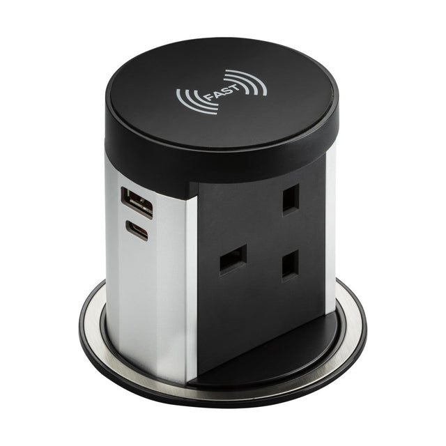 The 13A Pop Up Socket With Wireless Charger & Dual USB boasts a sleek silver and black design. It features a convenient wireless charging pad, complemented by a UK power socket, FASTCHARGE USB-A port, and USB-C port, making it perfect for desk or countertop installation.