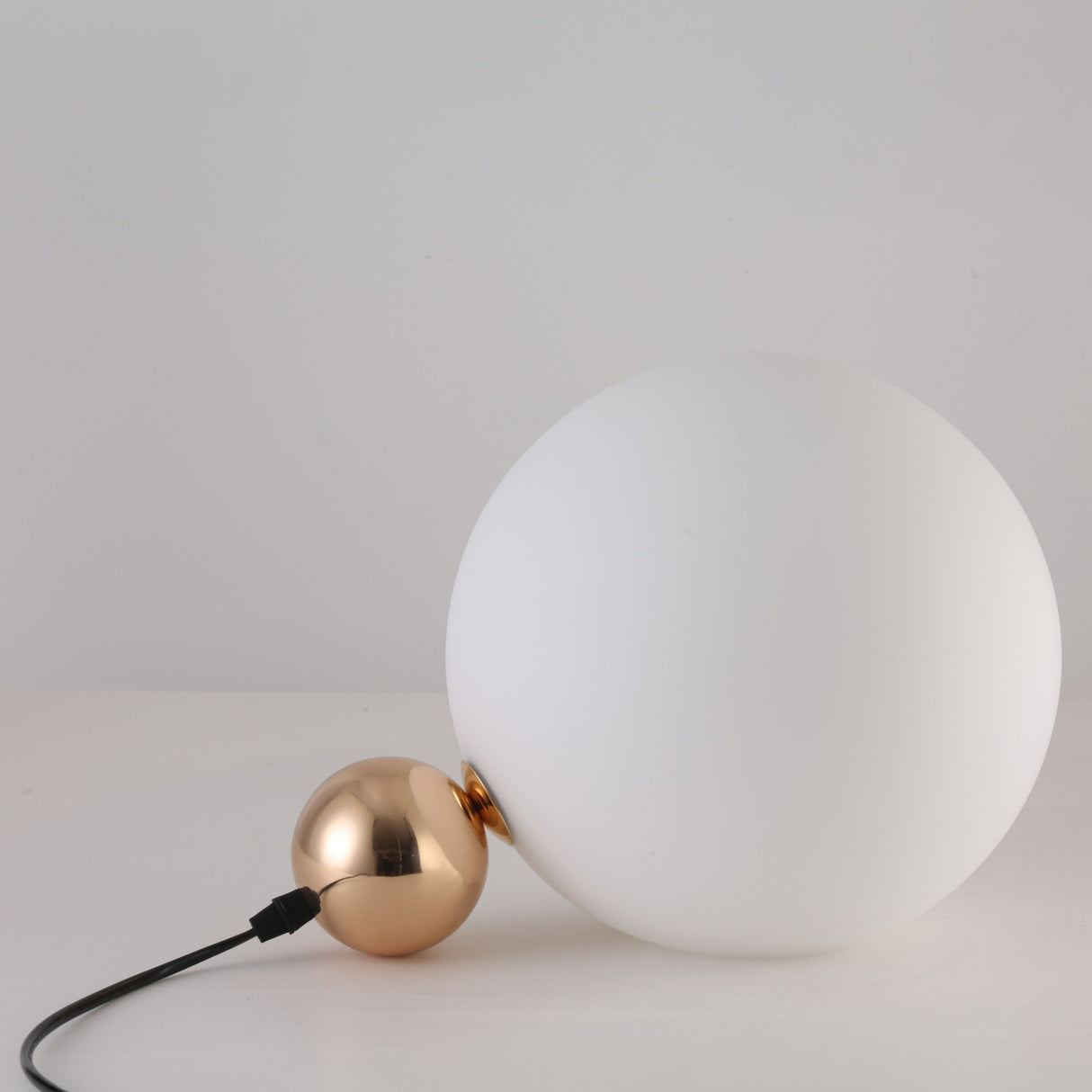 The Soul Table Lamp - Gold is a modern desk lamp with a large frosted white glass globe and a smaller gold sphere, joined by a black power cord, displayed against a plain white background.